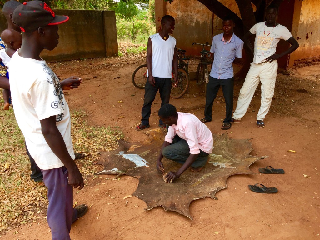 The actors putting the final touches on an animal hide used to sit on.