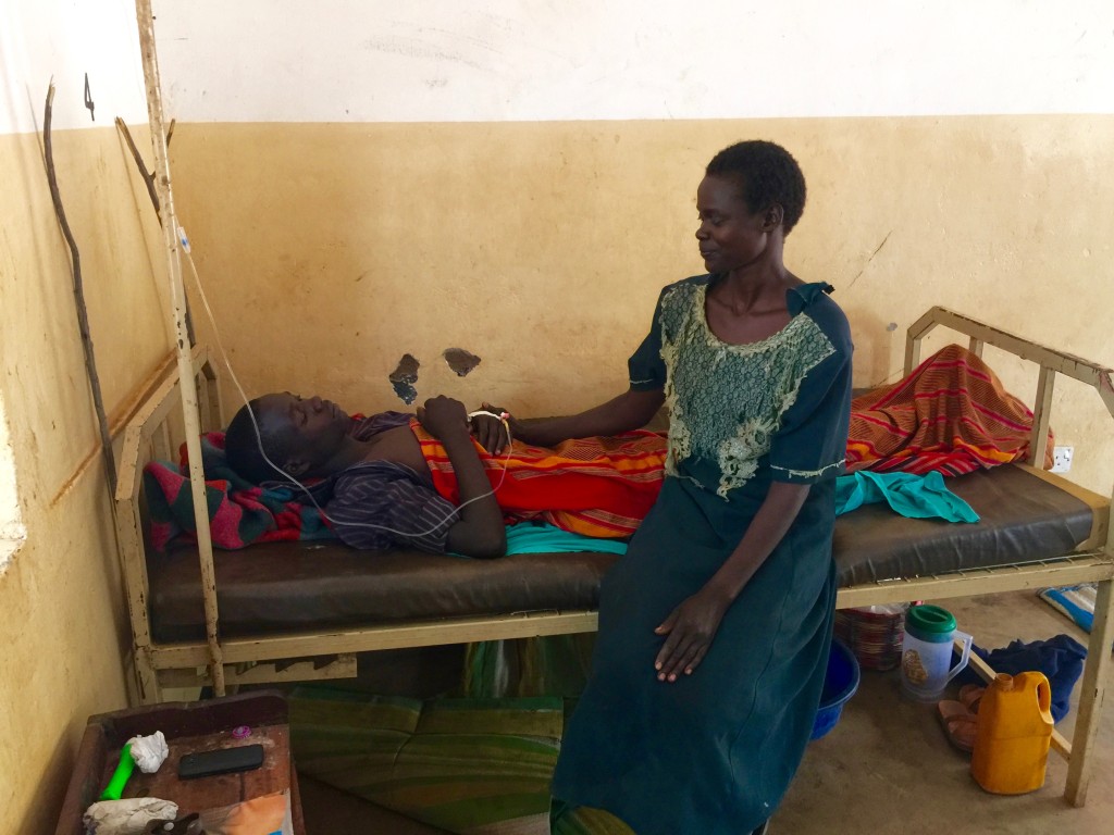 Mary Otema sits with her son who is very ill with malaria. 